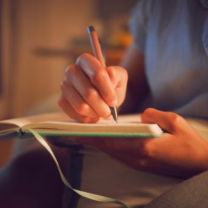 Creative writing at home by female hands enjoying a calm, peaceful day off indoors. Woman making notes in a journal, expressing her feelings and thoughts while making a note of a personal experience